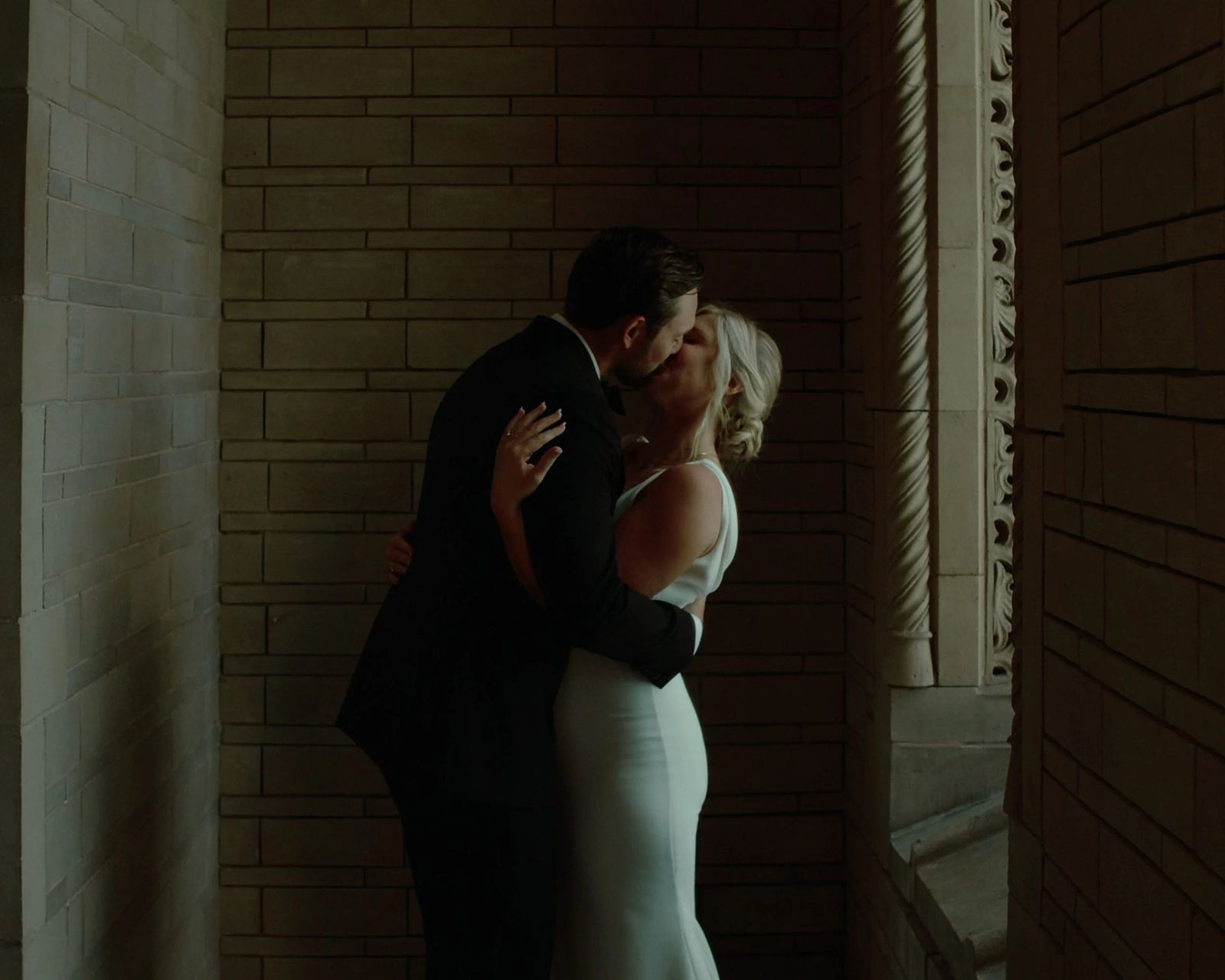Couple kissing in a shadowed stone corridor